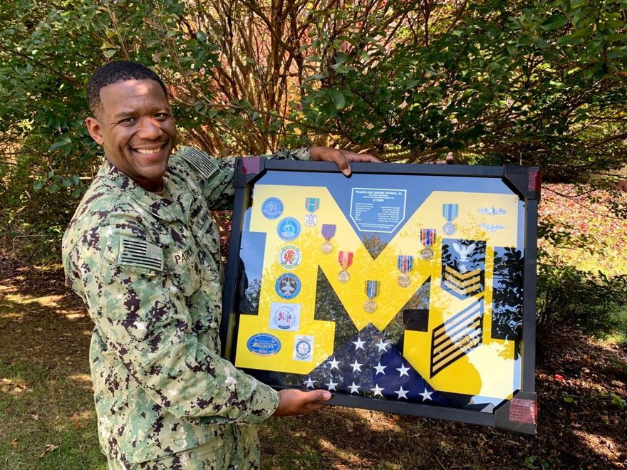 Jerome Patrick holding his Navy retirement shadow box, 22 years of service